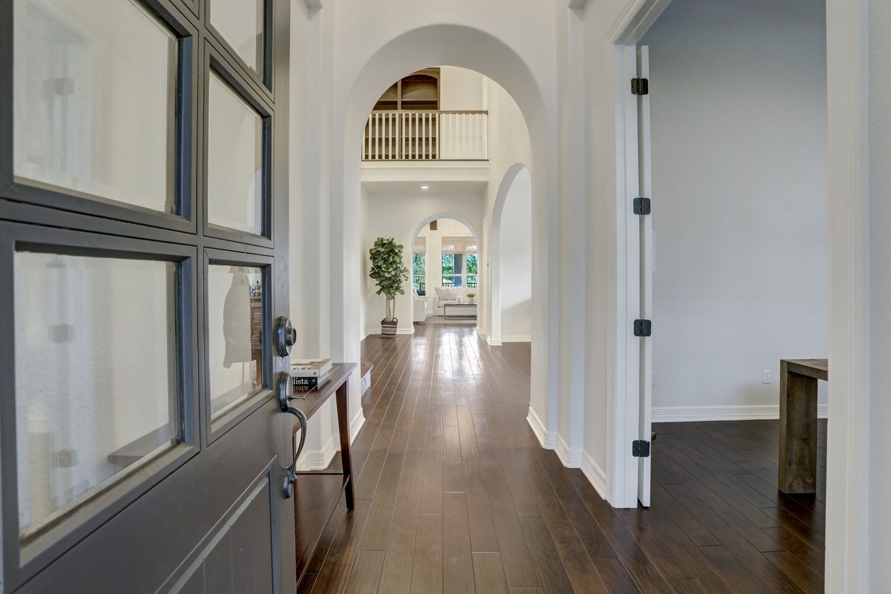 Entry hall seen through a glass-paned door, with a series of arches leading to the living room