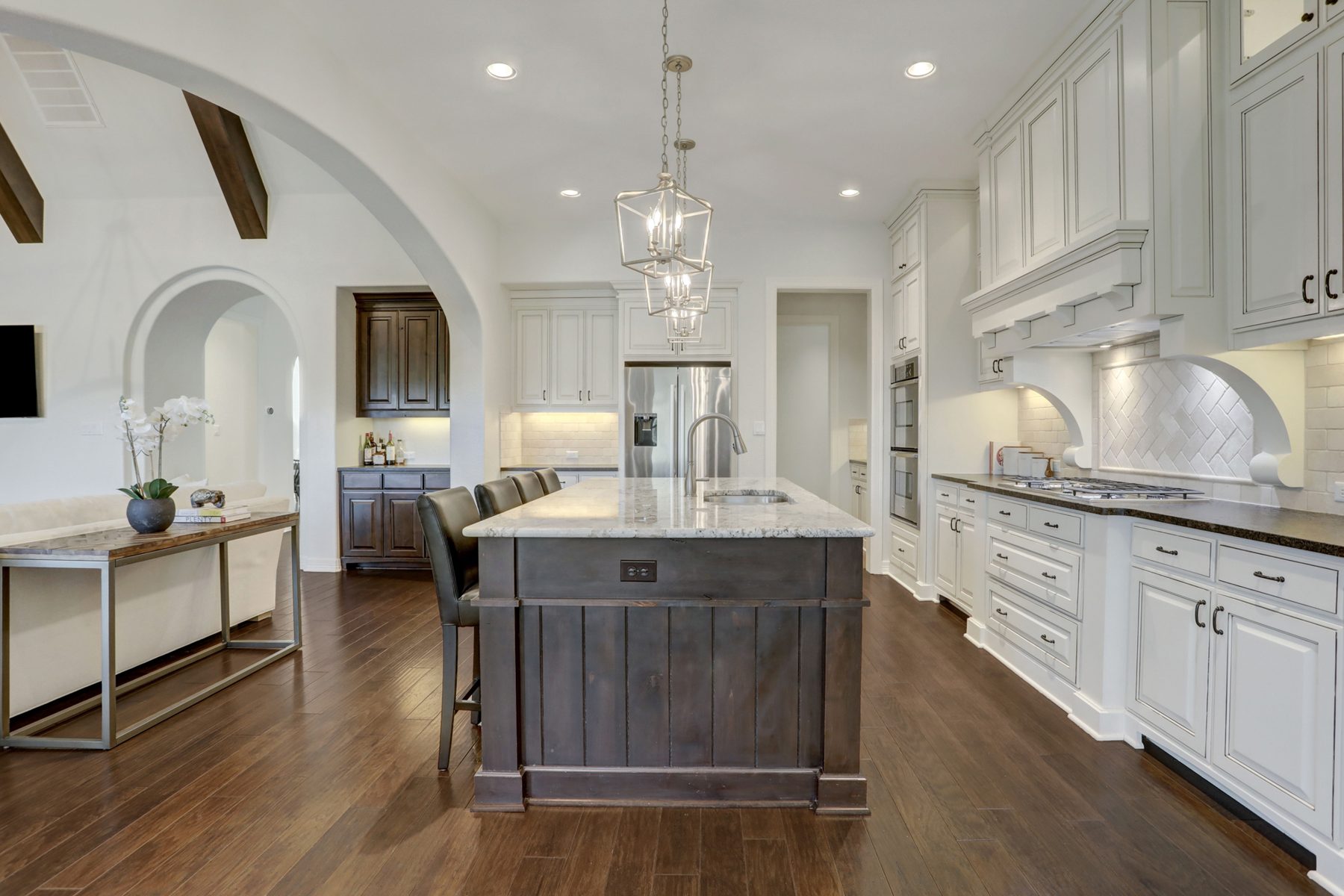 White kitchen with a dark stained island, granite counters and lantern pendants